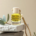 Small bottle of Luca & Grey Rosemary + Citrus essential oil on a stone surface with a beige background